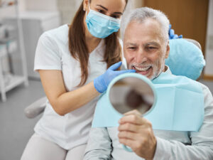 Senhor idoso sorrindo após colocar seu implante dentário